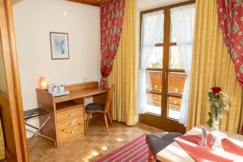 Schlafzimmer mit einem Schreibtisch, einem Bett und einem Fenster in der Unterkunft Bauernhofhotel "die Unterbergerin" - Zimmer mit Frühstück und Ferienwohnungen in Gastein mit GRATIS Thermeneintritt in Dorfgastein