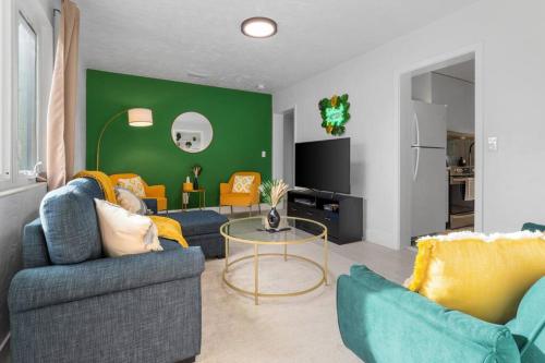a living room with two couches and a green wall at Smart Bungalow: 10-min to UF, Central Location in Gainesville