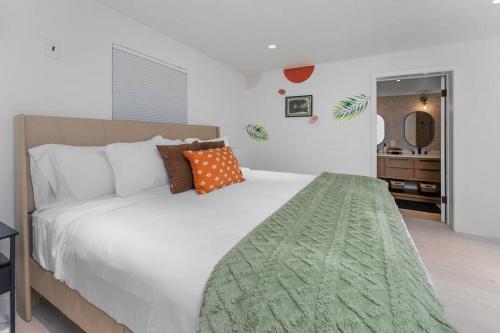 um quarto com uma grande cama branca com almofadas laranja em Smart Bungalow: 10-min to UF, Central Location em Gainesville