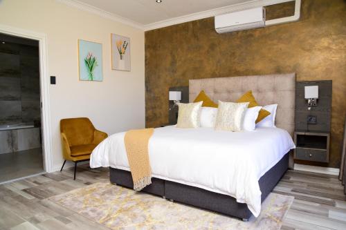 a bedroom with a large bed and a chair at Menucha Country Lodge in Mthatha