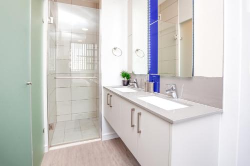 a white bathroom with a sink and a shower at Urban Oasis Apartments at The Median in Johannesburg