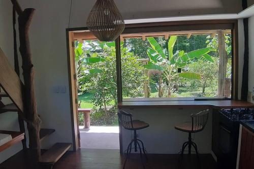 eine Küche mit zwei Hockern an einer Theke mit einem Fenster in der Unterkunft Boutique Beach Chalet, Luzimares, Serra Grande-BA in Serra Grande