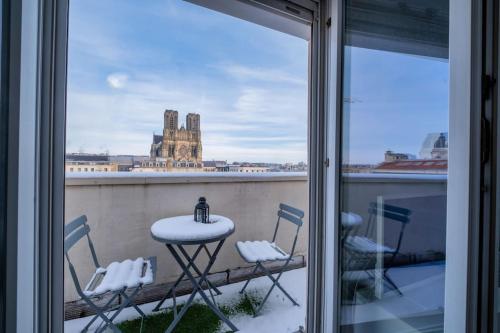 une table et des chaises sur un balcon avec vue sur un immeuble dans l'établissement Le Clovis - Cathédrale, à Reims