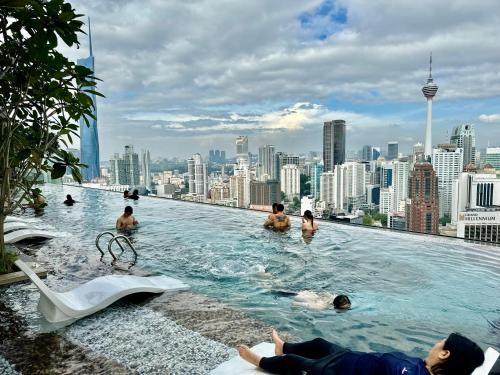 a group of people swimming in a pool on the roof of a building at Axon Residence By Classy 1 minutes Pavilion in Kuala Lumpur