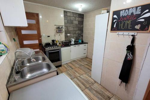 una pequeña cocina con fregadero y nevera. en Casa en el centro de Pirque en Pirque