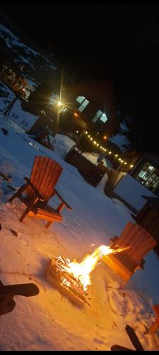 a fire burns in the snow next to a bench at Cabana Ioana-Horea in Horea