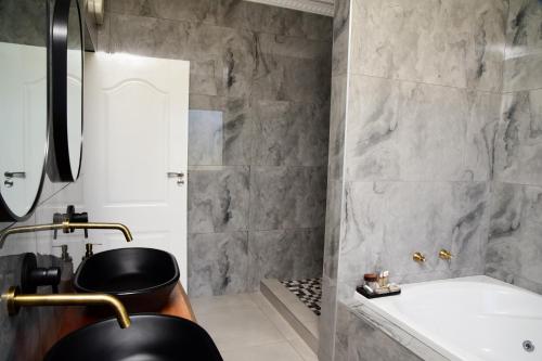 La salle de bains est pourvue d'une baignoire noire et d'un lavabo. dans l'établissement Menucha Country Lodge, à Mthatha