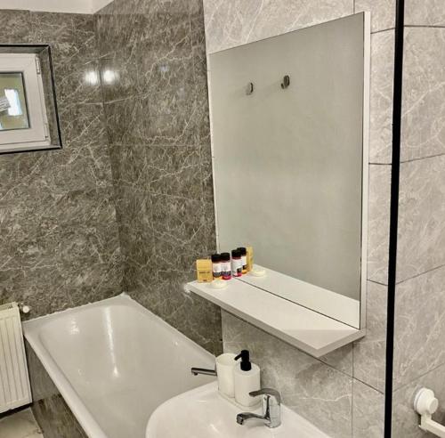 a bathroom with a sink and a mirror and a tub at Twins Apartments 2 in Ploieşti