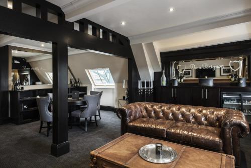 a living room with a leather couch and a table at The Vermont ApartHotel in Newcastle upon Tyne