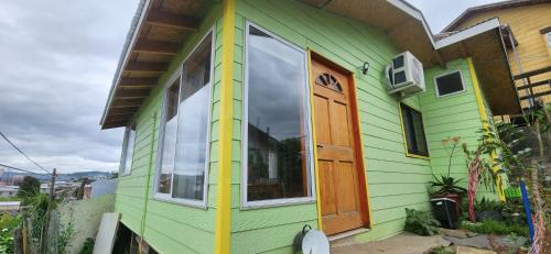 Casa verde y amarilla con puerta de madera en Alojamiento Danmar, en Quellón