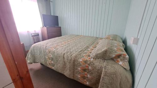 1 dormitorio con cama con edredón en Alojamiento Danmar, en Quellón