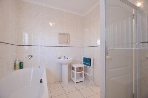 a bathroom with a tub and a sink and a shower at Family Tides in Yzerfontein