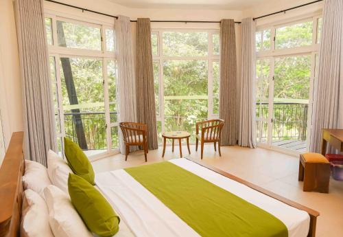 1 dormitorio con cama, mesa y ventanas en Roberosia - Holiday Home, en Kandy