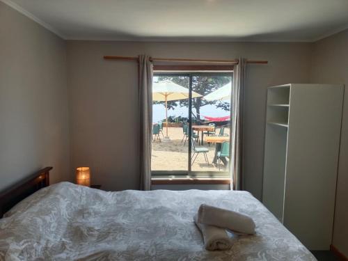 a bedroom with a bed and a view of a patio at Hostal Quiriyuca Sur in Horcón
