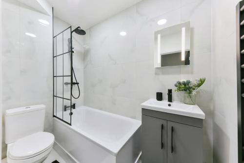 La salle de bains blanche est pourvue de toilettes et d'un lavabo. dans l'établissement Modern London Apartment with WIFI, à Norwood