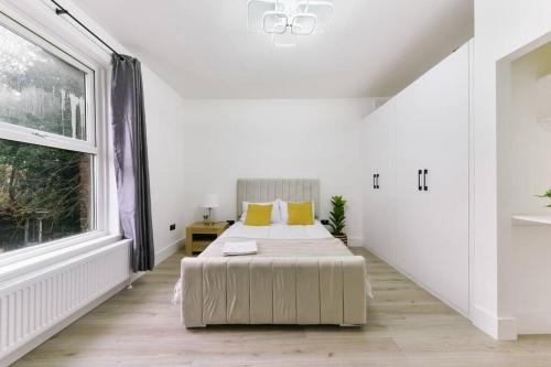 a white bedroom with a bed and a window at Modern London Apartment with WIFI in Norwood