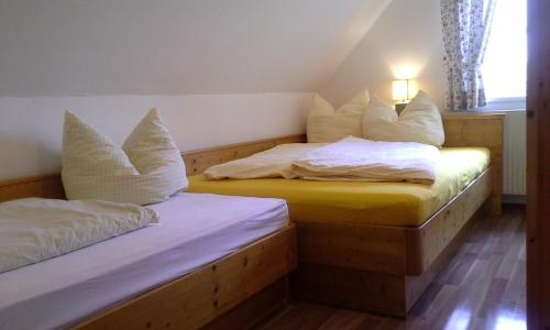 2 bedden in een kamer met witte lakens en kussens bij Ferienhaus Bad Waltersdorf in Bad Waltersdorf