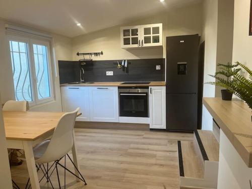 een keuken met een tafel en een zwarte koelkast bij Charmant appart 35m² dans villa in Saint-Laurent-du-Var