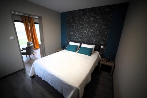 1 dormitorio con 1 cama blanca grande con almohadas azules en Chambres d'hôtes les Hirondelles, en Lanne-en-Barétous 