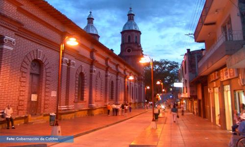 Una calle de la ciudad por la noche con gente caminando por la calle en Casa Leon - Supia, Caldas, en Supía