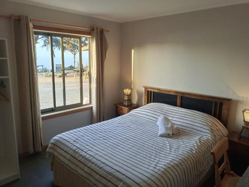 a bedroom with a bed with a white pillow on it at Hostal Quiriyuca Sur in Horcón