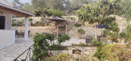 a garden with a stone wall and an umbrella at Alegria studios in Gaios