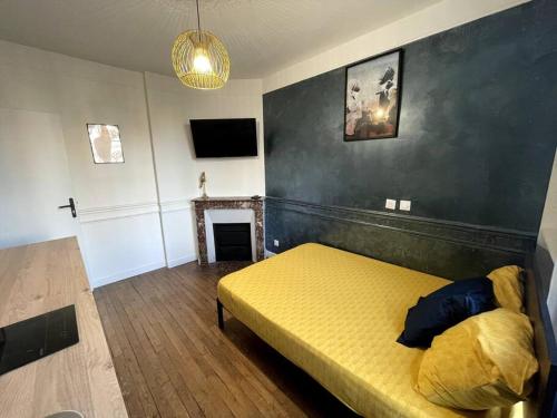 - une chambre avec un lit jaune et une cheminée dans l'établissement Studio Vintage : proche Paris, à Ivry-sur-Seine
