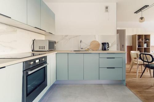 une cuisine avec des armoires blanches et une cuisinière dans l'établissement Haut Standing 8p, proche Disney, à Montévrain