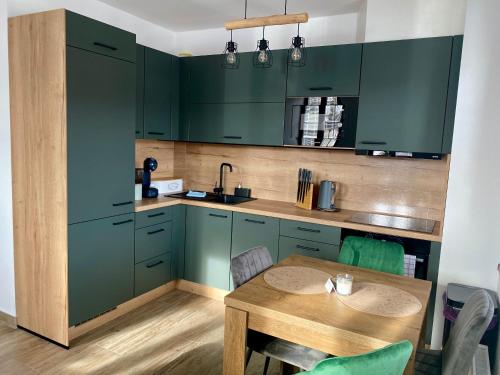 a kitchen with green cabinets and a wooden table at Apartmán v Kašperských Horách in Kašperské Hory