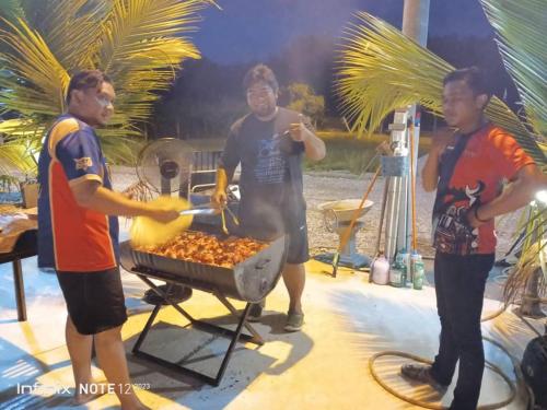 a group of men cooking food on a grill at Rumah Armand Studio Family Suite with Swimming Pool Pengkalan Balak Tg Bidara Masjid Tanah Melaka 