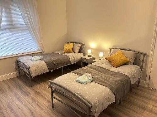2 camas individuales en una habitación con ventana en Cosy apartment with parking close to Ipswich station, en Ipswich