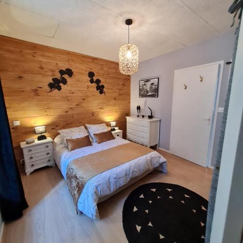 - une chambre avec un lit et un mur en bois dans l'établissement Bel appartement « Les Monts du Cantal », à Murat