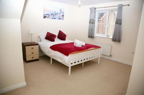 a bedroom with a white bed with red pillows at Stylish beautiful Lodge in Norwich in Norwich