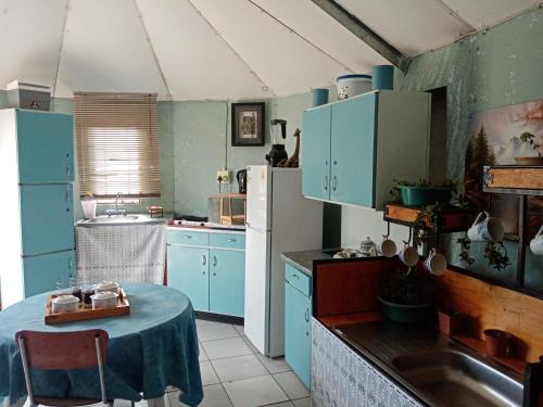 una cocina con armarios azules y una mesa. en Noble Luminous Accommodation & Tours, en Lafrenz Township