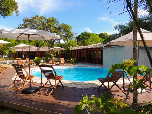 a deck with chairs and umbrellas next to a swimming pool at Pousada Maliale Boipeba in Ilha de Boipeba