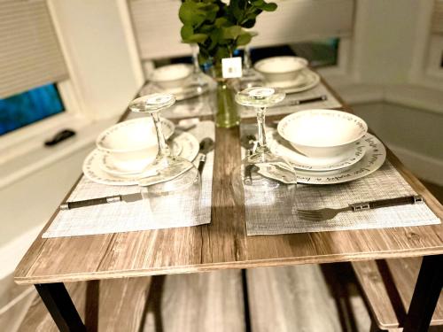a wooden table with plates and wine glasses on it at Cosy apartment with parking close to Ipswich station in Ipswich
