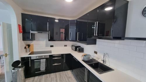 a kitchen with black and white cabinets and appliances at Seaside 2 bed flat sleeps 6 in Lee-on-the-Solent