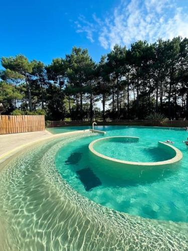 une piscine d'eau bleue et d'arbres dans l'établissement Appartement Lacanau Ocean - Golf, à Lacanau