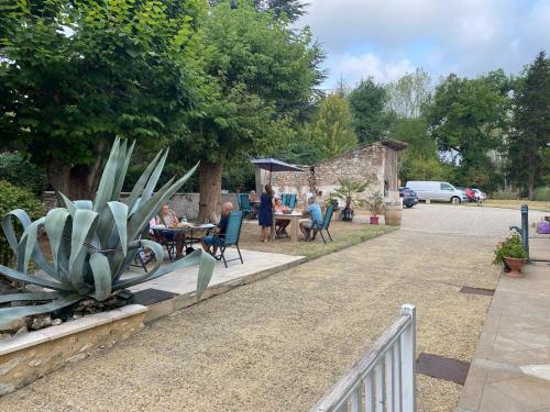 a group of people sitting at a table in a garden at Chambres et Gîtes Les Deux Chênes près de Bergerac in Le Fleix