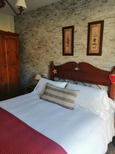 1 dormitorio con 1 cama blanca y 2 cuadros en la pared en BIESCAS PIRINEOS, en Biescas