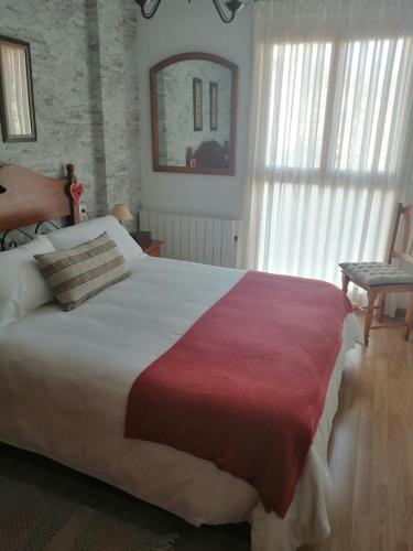1 dormitorio con 1 cama blanca grande con manta roja en BIESCAS PIRINEOS, en Biescas