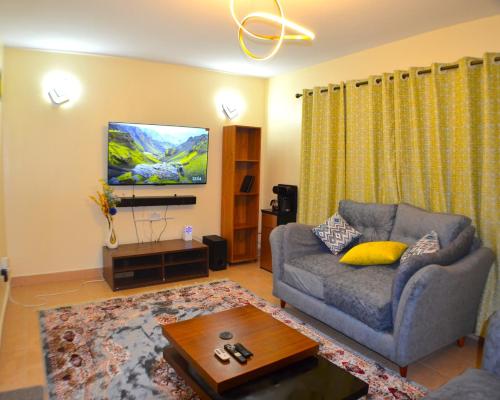 a living room with a couch and a tv at Bright Box 1 br near JKIA in Nairobi