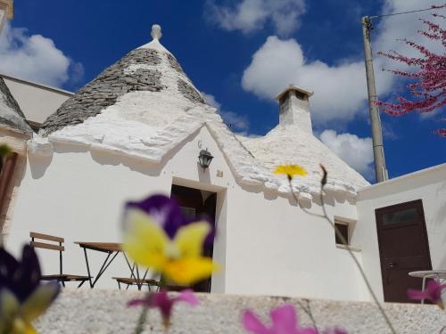 een witte kerk met een steil dak met paarse bloemen bij Trullo Il Giglio in Cisternino