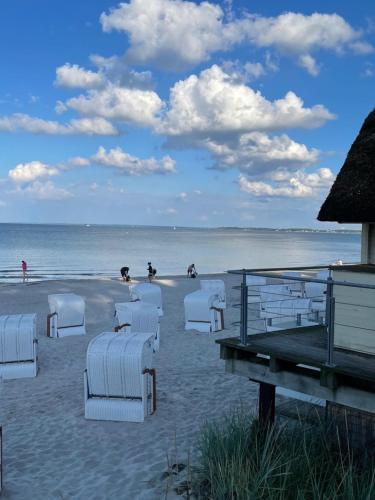 a group of white chairs on the beach at Traumhaftes Familiendomizil in Scharbeutz - Strand 500m, kostenlos Parken, Garten in Scharbeutz