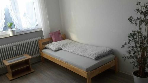 uma pequena cama num quarto com uma planta em Otthonos Szállás em Stuttgart