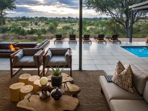 a living room with a fireplace and a pool at Kruger Lodge Mjejane in Hectorspruit