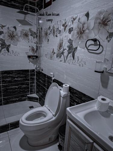 a bathroom with a toilet and a sink with flowers on the wall at wadi Rum bissan camp in Wadi Rum