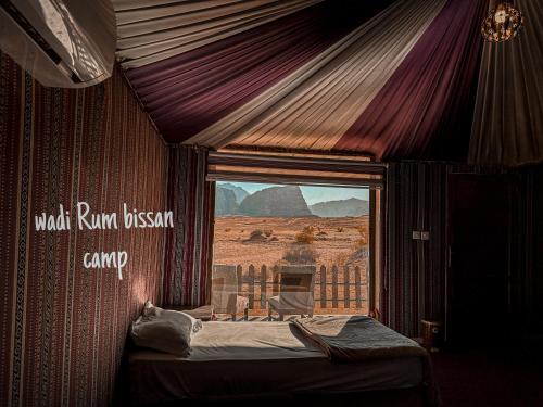 a tent with a view of the desert through a window at wadi Rum bissan camp in Disah