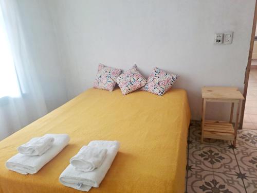 una camera da letto con un letto giallo e asciugamani di Rincón Verde Chacras de Coria a Ciudad Lujan de Cuyo