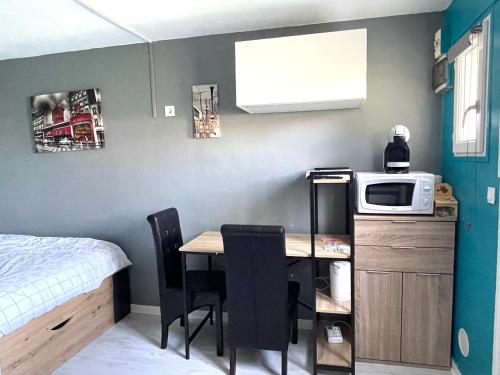 Studio cosy indépendant avec Jardin à Osny proche Cergy Pontoise في Osny: مطبخ صغير مع طاولة وميكروويف